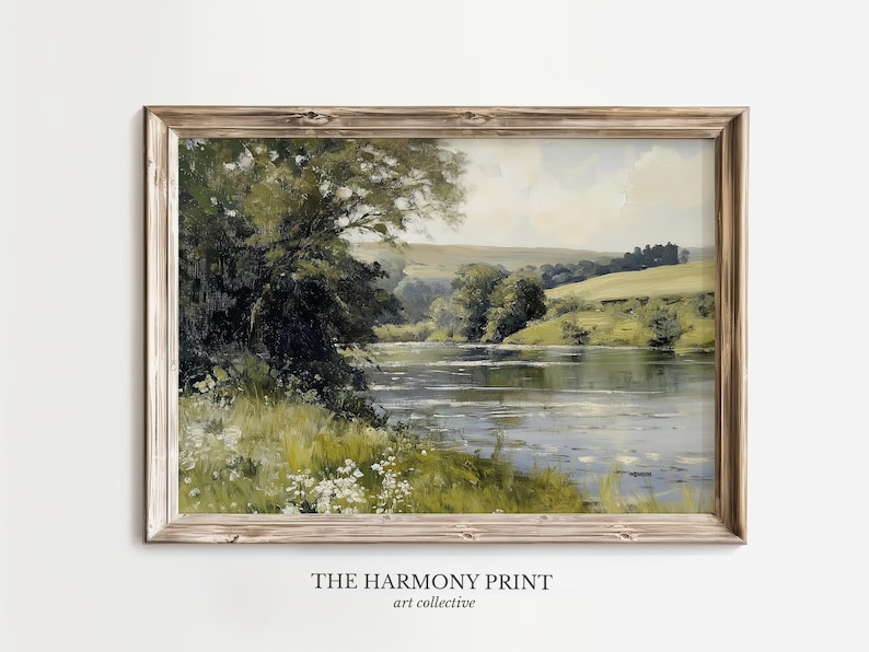 Pu&ograve; includere: Un dipinto incorniciato di una scena paesaggistica con un fiume, alberi e colline ondulate. Il dipinto &egrave; in una cornice di legno chiaro e ha un aspetto vintage.
