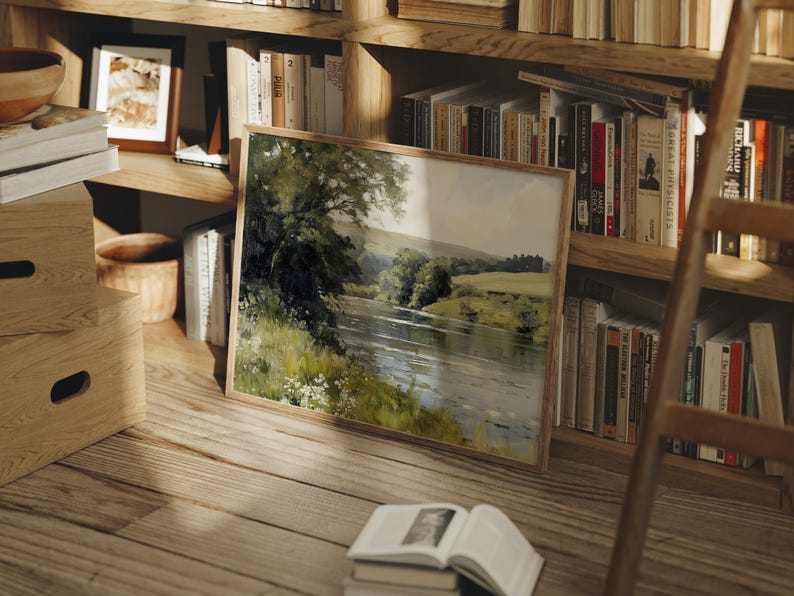 Pu&ograve; includere: Un dipinto incorniciato di una scena fluviale con alberi verdi e un cielo blu. Il dipinto &egrave; appeso a una libreria in legno con altri libri.