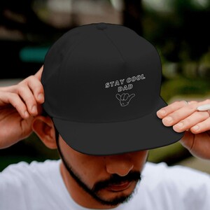 Könnte beinhalten: Schwarze Baseballkappe mit weißer Stickerei, auf der "Stay Cool Dad" mit einer Handgeste steht.
