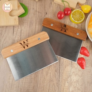 May include: Two wooden handled stainless steel dough cutters with personalized names. The top cutter has the name "Adelaide" with the letter "A" engraved on the handle. The bottom cutter has the name "William" with the letter "W" engraved on the handle.