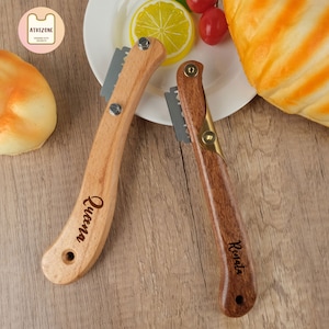 May include: Two wooden bread knives with serrated blades. The knives have personalized names, "Queen" and "Renata", engraved on the handles.