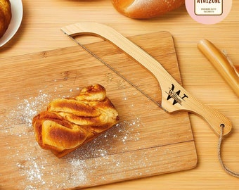 May include: A wooden bread knife with a wire blade and a personalized inscription that reads "William". The knife is on a wooden cutting board with a loaf of bread and powdered sugar.