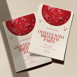 May include: Red and white invitation for Olivia's 30th birthday party. The invitation features a red disco ball graphic and the text "You're invited to Olivia's 30th Birthday Party". The invitation also includes the date, time, and location of the party.