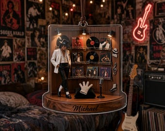 May include: A decorative acrylic hanging ornament featuring a miniature figure of a performer in a white blazer and black trousers, standing next to a display of vinyl records, a microphone, and a sequined glove, with the name Michael engraved.