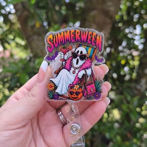 May include: A clear acrylic badge reel featuring a ghost wearing sunglasses and a pink feather boa, lounging in a beach chair with a cocktail. The text SUMMERWEEN is printed in pink and orange at the top, with a jack-o'-lantern and flowers below.