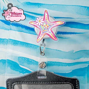 May include: A retractable badge reel featuring a pink starfish design with a white daisy accent. The starfish has yellow, blue, and pink details. The reel is attached to a clear plastic ID holder, with the text "Watson DavidStore" on a pink cloud.