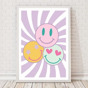 May include: A framed art print featuring three smiley faces in pink, yellow, and mint green. The pink smiley face has teal eyes, the yellow one has purple star eyes, and the mint green one has heart eyes. The background is a light purple and white striped design.