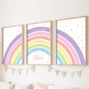 Op de afbeelding: Drie ingelijste wandposters met een pastelkleurig regenboogontwerp met geschulpte randen en kleurrijke stippen. De middelste poster bevat de tekst: I can do great things, believe in myself, I try my best, I never give up, my life is magic en de naam Olivia.