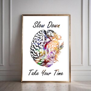 May include: A framed art print featuring a detailed illustration of a brain split in half, one side a realistic brain and the other a colorful floral design. The words "Slow Down" and "Take Your Time" are written in elegant script.