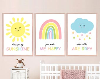 Puede incluir: Tres impresiones coloridas con ilustraciones de un sol, un arcoíris y una nube con lluvia. El sol tiene una cara sonriente y el texto "You are my sunshine". El arcoíris tiene una cara sonriente y el texto "You make me happy". La nube tiene una cara sonriente y el texto "When skies are grey".