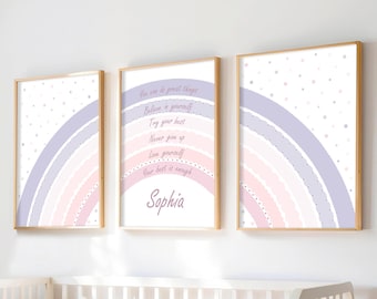 May include: Three framed art prints with a rainbow design in pastel pink, lavender, and white. The center print features the name "Sophia" and inspirational text. The prints are displayed above a white crib.