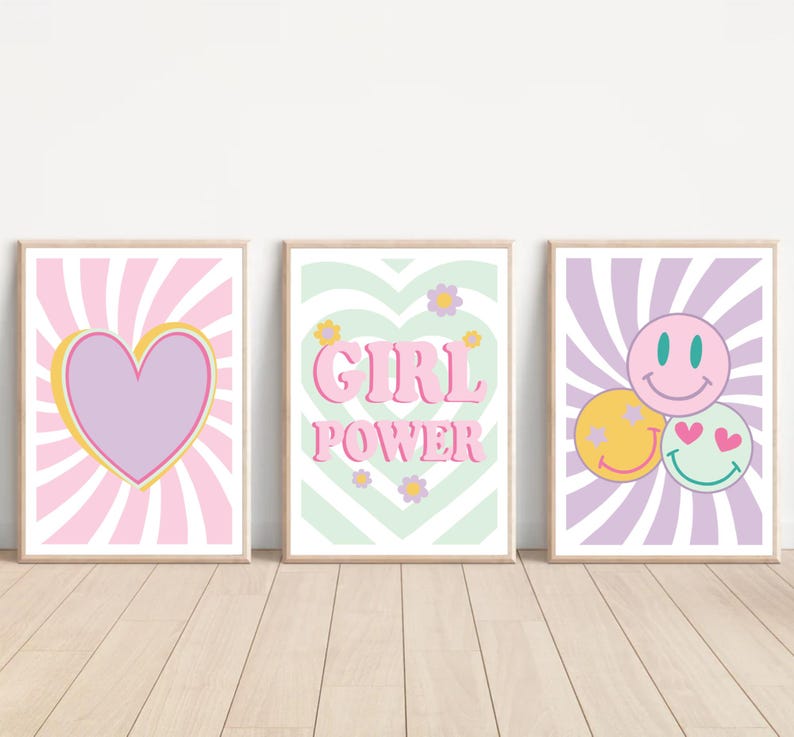 May include: Three framed art prints with retro designs. The first features a purple heart with a yellow outline against a pink and white striped background. The second says "GIRL POWER" in pink letters. The third has three smiley faces.