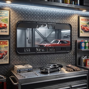 May include: A black metal mirror with a New York skyline cutout and the text "USA New York USA" is mounted on a textured metal wall. A black classic car model, mechanic manuals, and tools sit on a metal cabinet. Racing posters are on the wall.