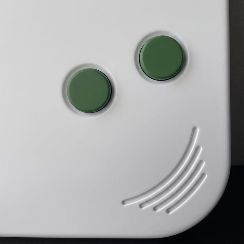May include: Close-up of a white, rounded corner object with two green circular buttons and a curved, ridged design. The buttons are recessed into the surface, and the ridges are slightly raised.