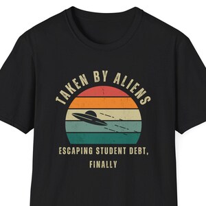 Op de afbeelding: Zwart T-shirt met een retro design met een UFO boven een zonsondergang. De tekst luidt "TAKEN BY ALIENS" boven de afbeelding en "ESCAPING STUDENT DEBT, FINALLY" eronder. Een leuke, novelty tee.