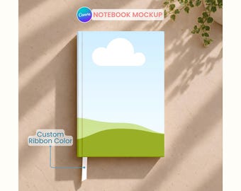 May include: A notebook with a hard cover featuring a graphic print of a light blue sky, a single white cloud, and a green grassy hill. The notebook includes a white ribbon bookmark extending from the bottom edge of the spine.