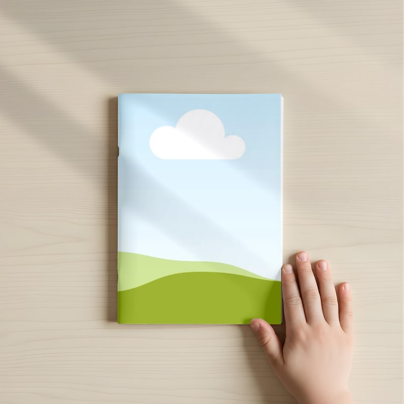 May include: A children's book with a cover featuring a blue sky, a white cloud, and green rolling hills. The book is on a light wood surface, with a child's hand partially visible.