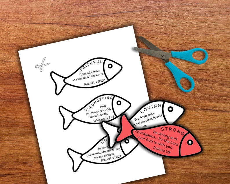 May include: A white paper with fish-shaped cutouts, each with a word and Bible verse. One fish is red. Blue scissors are on a wooden surface.