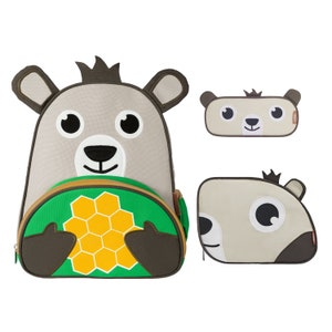 May include: A gray and brown backpack with a bear face and a green honeycomb design. The backpack has a zipper closure and a small pocket on the front. There is also a matching gray and brown pencil case with a bear face.