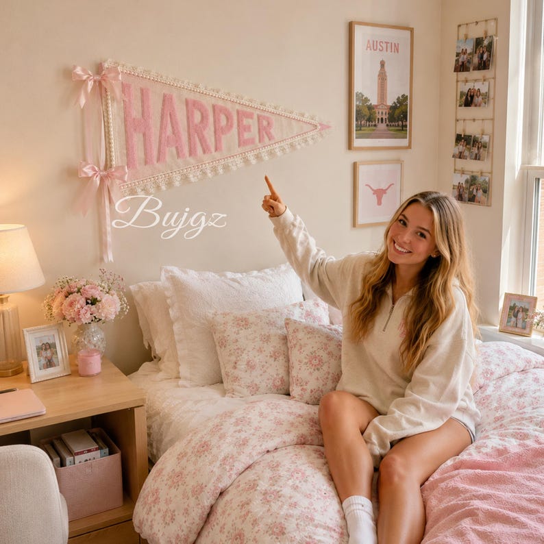 May include: A triangular fabric wall pennant featuring the name HARPER in large pink felt letters. The pennant is trimmed with white lace and decorated with two light pink satin ribbons tied at the left side, hanging on a plain wall.