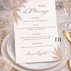 Peut inclure: Un menu de mariage avec l'inscription "Menu de Mariage" en écriture élégante. Le menu comprend du texte français pour les plats : Entrée, Plat, Dessert et Boissons. La carte est ornée d'éléments floraux et repose sur une assiette blanche avec des couverts dorés.