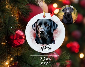 May include: A white ceramic Christmas ornament with a watercolor painting of a black Labrador Retriever. The dog's name, "Nikita", is written in black script below the image. The ornament is 2.87 inches in diameter.