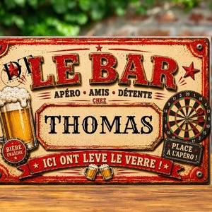 May include: A vintage-style wooden sign with the words "LE BAR" in red, featuring a beer mug, a dartboard, and the name "THOMAS." The sign also includes French phrases like "Apéro, Amis, Détente."