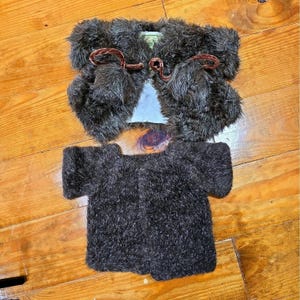 May include: A dark brown faux fur bolero jacket with a light blue lining and brown velvet toggle closures, paired with a matching dark brown faux fur short-sleeved top. Both garments feature a textured, shaggy pile finish throughout the fabric.