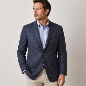 May include: A navy blue blazer with a two-button closure, paired with a light blue button-down shirt and khaki pants. The blazer has a textured appearance and a classic fit, suitable for business or casual wear.