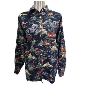 May include: Dark navy button-down shirt with a repeating pattern of foxes, deer, mountains, and foliage. The long-sleeved shirt has a collared neckline and gold-colored buttons. The overall design has a vintage, outdoorsy aesthetic.