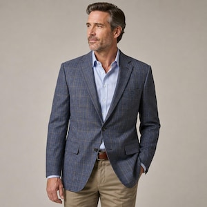 May include: A blue plaid blazer with a light blue dress shirt and khaki pants. The blazer has a two-button closure and a brown leather belt. The man is looking to the side.