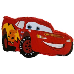 Puede incluir: Una piñata roja de Rayo McQueen con neumáticos negros y el número 95 en amarillo. El coche tiene una cara sonriente y las palabras "Anthony Andy" en el neumático. Una divertida decoración para fiestas.