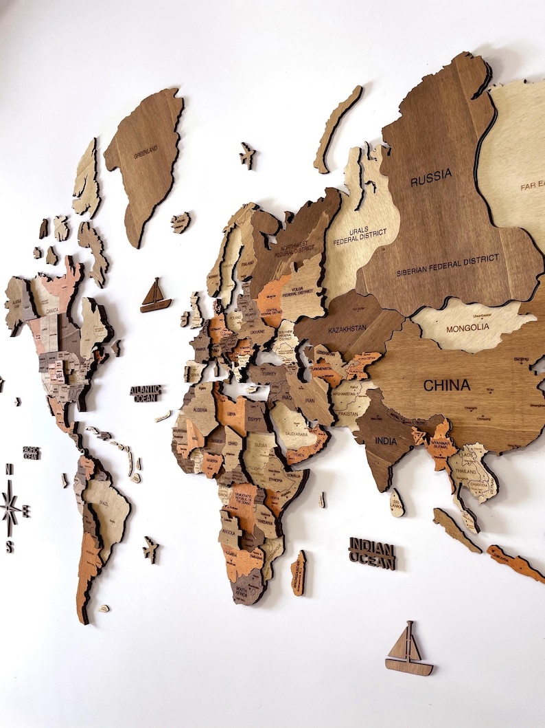 K&ouml;nnte beinhalten: Ein Puzzle einer Weltkarte aus Holz in verschiedenen Braunt&ouml;nen. Die Karte ist in L&auml;nder und Kontinente unterteilt. Die Karte enth&auml;lt die Namen von L&auml;ndern und Kontinenten wie Russland, China, Indien und der Indischer Ozean.