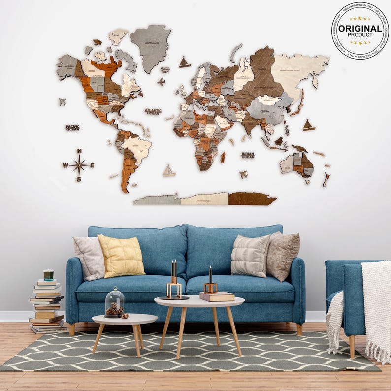 K&ouml;nnte beinhalten: Eine Weltkarte aus Holz mit einem Kompass und einem blauen Sofa im Vordergrund. Die Karte ist aus verschiedenen Holzschattierungen gefertigt und hat einen hellgrauen Hintergrund. Das Sofa ist hellblau und hat zwei Kissen. Die Karte h&auml;ngt an einer wei&szlig;en Wand.
