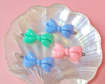 Set of 4 vintage hair clips from the 70s and 80s. Made of plastic, shaped like ribbon bows with star patterns.