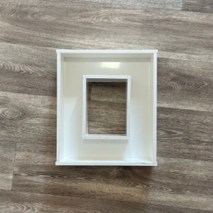 May include: White picture frame with a smaller white picture frame inside. Both frames are empty.