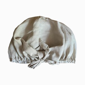 May include: A light beige linen hair wrap with a gathered elastic band and a tie at the top.