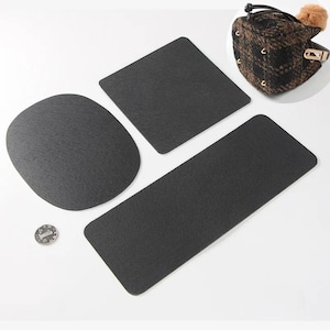 May include: A selection of black felt pads in different shapes: a rectangle, a square, and an oval. A coin is next to the pads. A patterned hat with a fur pom-pom is in the upper right corner.