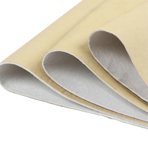 May include: A stack of folded sheets featuring a smooth, light tan exterior surface and a soft, white, fibrous interior lining. The material is layered in overlapping folds, revealing the contrast between the tan outer layer and white inner side.