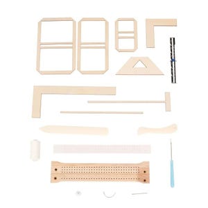 Op de afbeelding: Een knutselset met diverse houten componenten, waaronder rechthoekige frames, een driehoekig stuk en een geperforeerde houten basis. Ook inbegrepen zijn een spoel witte draad, een naald en andere kleine gereedschappen. De stukken zijn op een witte achtergrond geplaatst.
