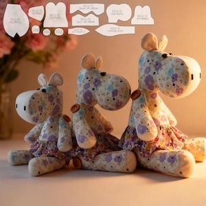 May include: Three handmade stuffed hippos with floral fabric bodies and button details. Each hippo has a cream-colored head and ears, and wears a floral skirt. Sewing patterns are visible in the background.