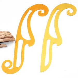 Puede incluir: Dos reglas de curva francesa de color amarillo dorado con un diseño curvo. Las reglas tienen un acabado liso y brillante y están diseñadas para trabajos de dibujo y diseño. Las reglas están hechas de un material duradero.