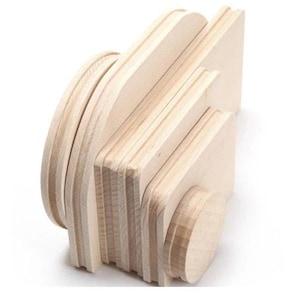 May include: A wooden camera toy, constructed from light-colored wood. The camera features a lens, a rectangular body, and a curved top, all made from layered wooden pieces. The design is simple and minimalist, with a focus on the natural wood grain.