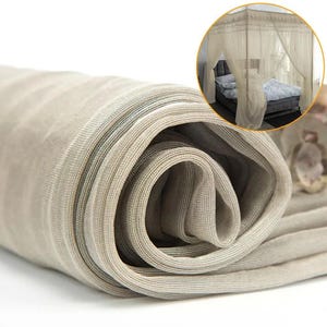 Puede incluir: Tela de mosquitera beige enrollada. La tela está finamente tejida con un sutil patrón de rayas. Una incrustación circular muestra la red drapeada alrededor de un marco de cama, lo que sugiere su uso como dosel.