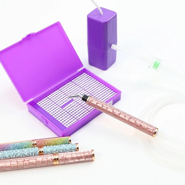 May include: A set of nail art tools, including a pink crocodile-textured pen, a purple container with white beads, and several other pens with glitter and crocodile textures. The tools are for nail art.