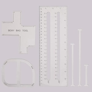 May include: A set of clear acrylic sewing tools, including a ruler with inch measurements, a curved template, and a "BOXY BAG TOOL" template. The ruler is marked up to 27 cm. The templates have measurements in inches.
