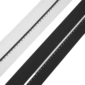 May include: Two parallel strips of fabric, one white and one black, each featuring a single straight line of stitching running lengthwise along the center. The stitching creates a subtle, dashed pattern that contrasts with the solid color of the fabric.