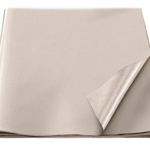 Puede incluir: Una hoja de papel beige doblada, con una esquina levantada que revela una superficie más clara y brillante debajo. El papel tiene una textura suave y parece nuevo.