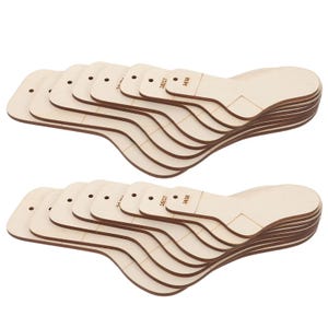 Puede incluir: Dos pilas de hormas de zapatos de madera sin terminar. Cada horma tiene una forma curva con una punta redondeada y un talón. Las hormas tienen un agujero cerca de la punta y marcas que dicen "15/27" y "14/25".