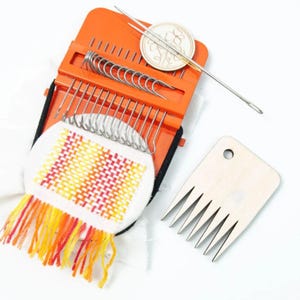 May include: An orange weaving kit containing a needle, hooks, and a wooden comb. The kit features a small, colourful woven piece with orange, yellow, and red fringe. A small wooden disc with a floral design is also included.